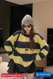 Person wearing a yellow and blue striped sweater with a gray beanie and sunglasses indoors.