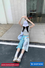 Person sitting on the ground with a white bucket hat, wearing a light-colored top and blue patterned pants, with a shopping cart icon and text overlay.