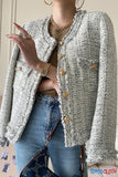 Person wearing a textured gray cardigan with gold buttons, blue jeans, and holding a patterned bag.