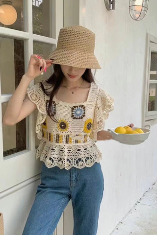 Woman wearing a crochet top and holding a bowl of lemons in a white-walled room.