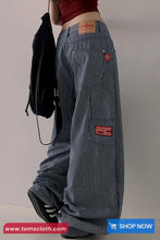 Person wearing blue corduroy pants with visible branding, standing against a plain background.