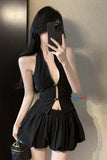 Person wearing a black dress with cut-out design, holding a phone.