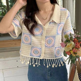 Woman wearing a colorful crochet cardigan with a floral arrangement in the background
