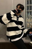 Person wearing a black and white striped sweater in an indoor setting.