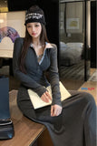 Woman sitting on a bed wearing a dark hoodie and black beanie with text, in a bedroom setting.