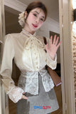 Person wearing a white lace blouse and gray skirt, waving at the camera.