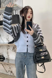 Woman taking a mirror selfie wearing a striped sweater and jeans, holding a black backpack.