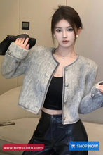 Woman wearing a gray textured jacket with a blurred background