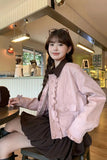 Woman sitting at a cafe wearing a pink jacket and black skirt.