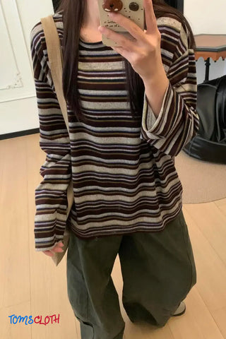 Person wearing a striped sweater and taking a mirror selfie indoors.
