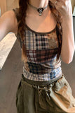 Person wearing a plaid tank top and brown pants with a neutral background