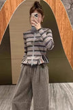 Person wearing a striped sweater and gray pants taking a mirror selfie.