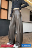 Person wearing brown leather pants and a black top in an indoor setting.