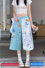 Person wearing colorful pants with sea-themed designs in an indoor setting.