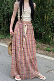 Woman wearing a plaid skirt and white top outdoors
