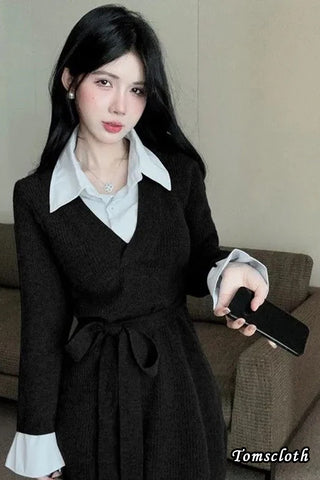 Woman in a black coat holding a phone indoors