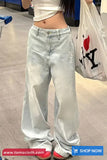 Person wearing light blue jeans and a white crop top, holding a transparent bag with a logo.