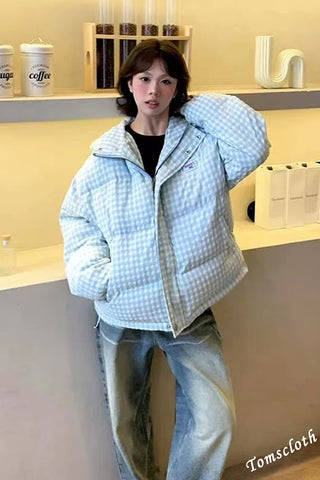 Person wearing a light blue checkered puffer jacket in an indoor setting
