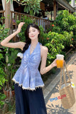 Woman in a blue dress holding a drink and a bag with plants in the background