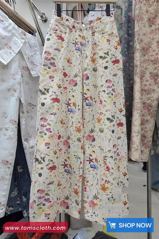 Floral patterned pants hanging on a rack with 'www.tomscloth.com' branding.