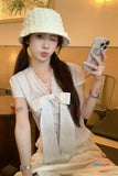Woman taking a selfie wearing a white hat and striped shirt with a large bow.