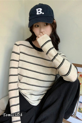 Person wearing a black and white striped sweater and a black cap with a 'B' logo.