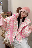 Woman wearing a pink floral coat and matching hat indoors.