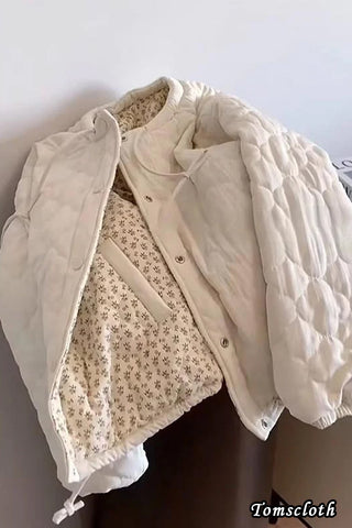 Beige quilted jacket over a floral dress on a plain background