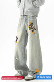 Light gray jeans with colorful floral embroidery on a white background
