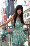 Woman in a striped dress standing on a balcony with a cityscape background