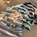 Three folded striped shirts on a textured surface