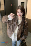 Woman wearing a brown coat with a lace top in an indoor setting