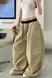Person wearing beige wide-leg pants and a white top in an indoor setting with 'TomsCloth' branding.