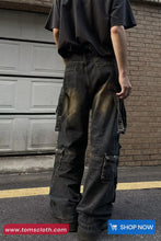 Person wearing dark jeans and a black shirt standing in front of a garage door.