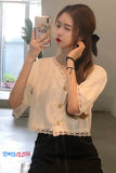 Woman taking a mirror selfie wearing a light-colored blouse with lace details.