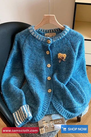 Blue knitted cardigan on a hanger with a visible brand tag, displayed indoors.