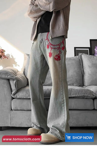 Person wearing gray sweatpants with red designs in a living room setting.