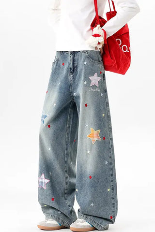 Person wearing blue jeans with star patterns, holding a red bag on a white background