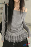 Person wearing a gray off-shoulder top with lace details, standing indoors.