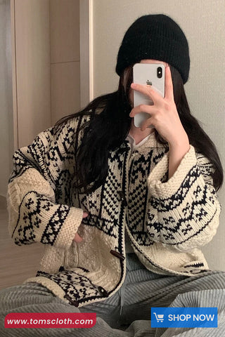 Person wearing a patterned cardigan taking a mirror selfie.