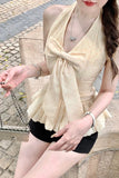 Woman wearing a beige scarf and black shorts sitting on a stone bench.