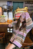 Person wearing a striped cardigan and pink beanie in a coffee shop setting