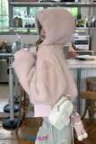 Person wearing a pink hooded coat with fur trim in a kitchen setting