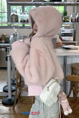 Person wearing a pink hooded coat with fur trim in a kitchen setting