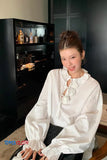 Woman in a white blouse sitting in a room with a dark background