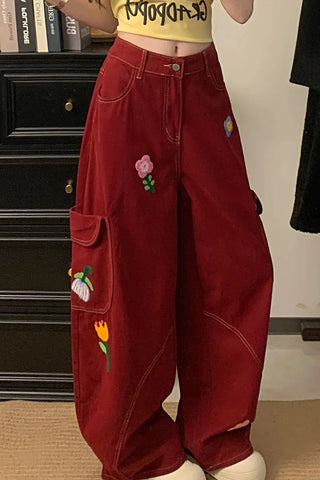 Person wearing red pants with colorful patches in a room.