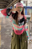 Person wearing a colorful striped sweater and pink cap at a bus stop.