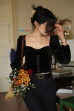Woman in a black outfit holding flowers indoors