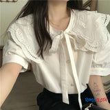 Person wearing a white lace blouse with a blurred background