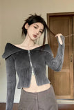 Woman wearing a gray off-shoulder zip-up sweater in an indoor setting.